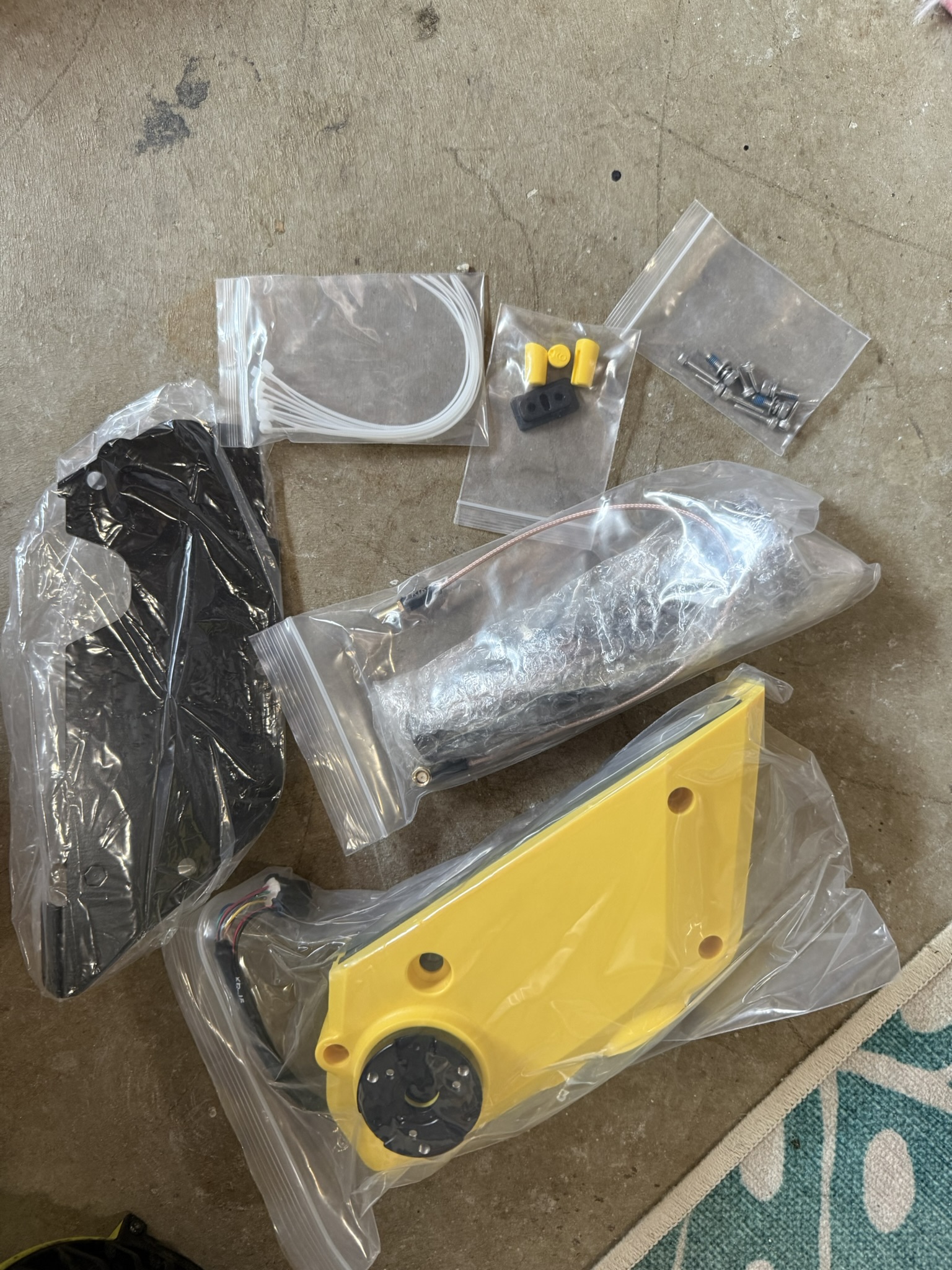 Box of Yarbo replacement parts including camera, cables and cover dumped on a garage floor with no instructions